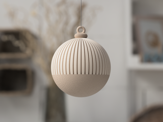 Beige  ornament with textured surface hanging against a neutral background