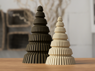 Two 3D-printed Christmas tree-shaped objects, one in green and one in red, are displayed on a wooden surface.
