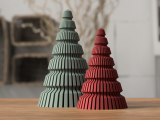 Two decorative Christmas trees, one green and one red, on a wooden surface with a blurred background.