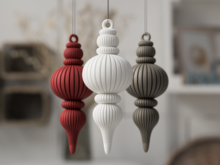 Three decorative ornaments in red, white, and sage green hanging against a blurred indoor background.