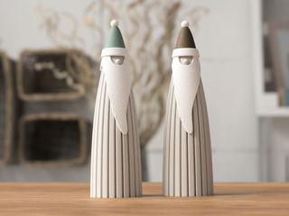 Two small figurines of Santa Claus on a wooden surface.